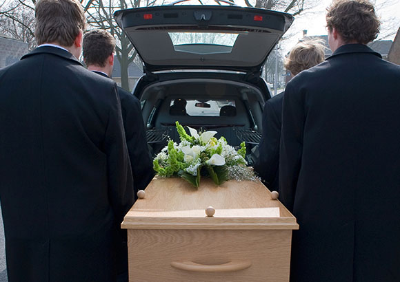 four men holding a casket to place into a hearse